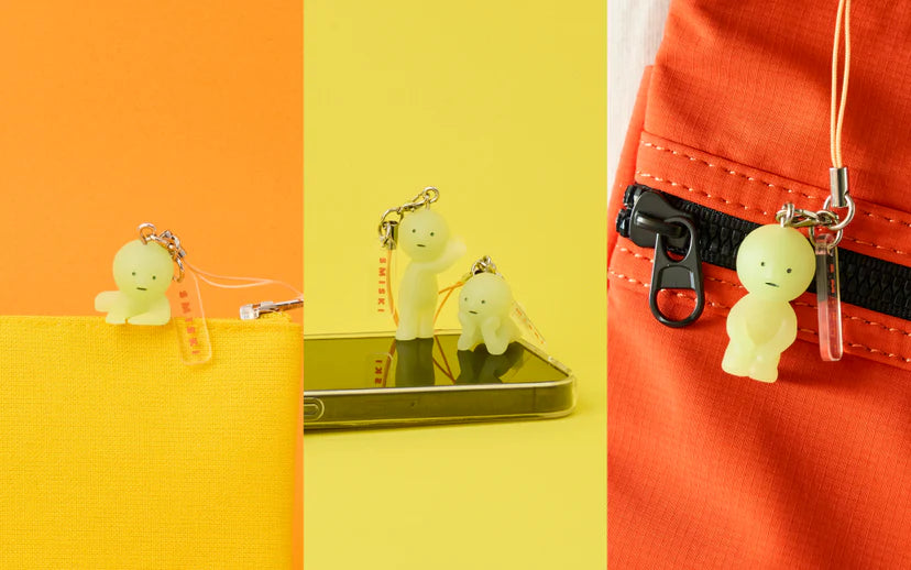 SMISKI Strap Accessory - Series 2, glow-in-the-dark figures, clipped to a zipper and standing on a smartphone, novelty charms with unique personalities.