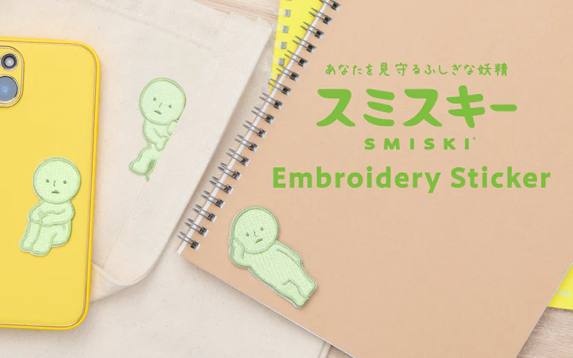 SMISKI Embroidery Sticker featuring three pale-green figures on a phone case, tote, and notebook, embodying a mysterious fairy watching over you.