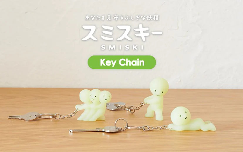 Smiski Keychains glowing in the dark on a table, featuring small figurines with keys attached, perfect for finding and protecting your keys.