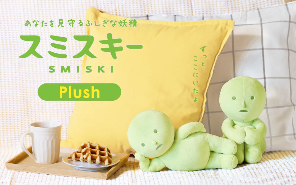 SMISKI Plush: Two lime-green plush figures on a sofa, one reclining, one sitting, with a cozy setting of a cushion, mug, and waffles nearby.