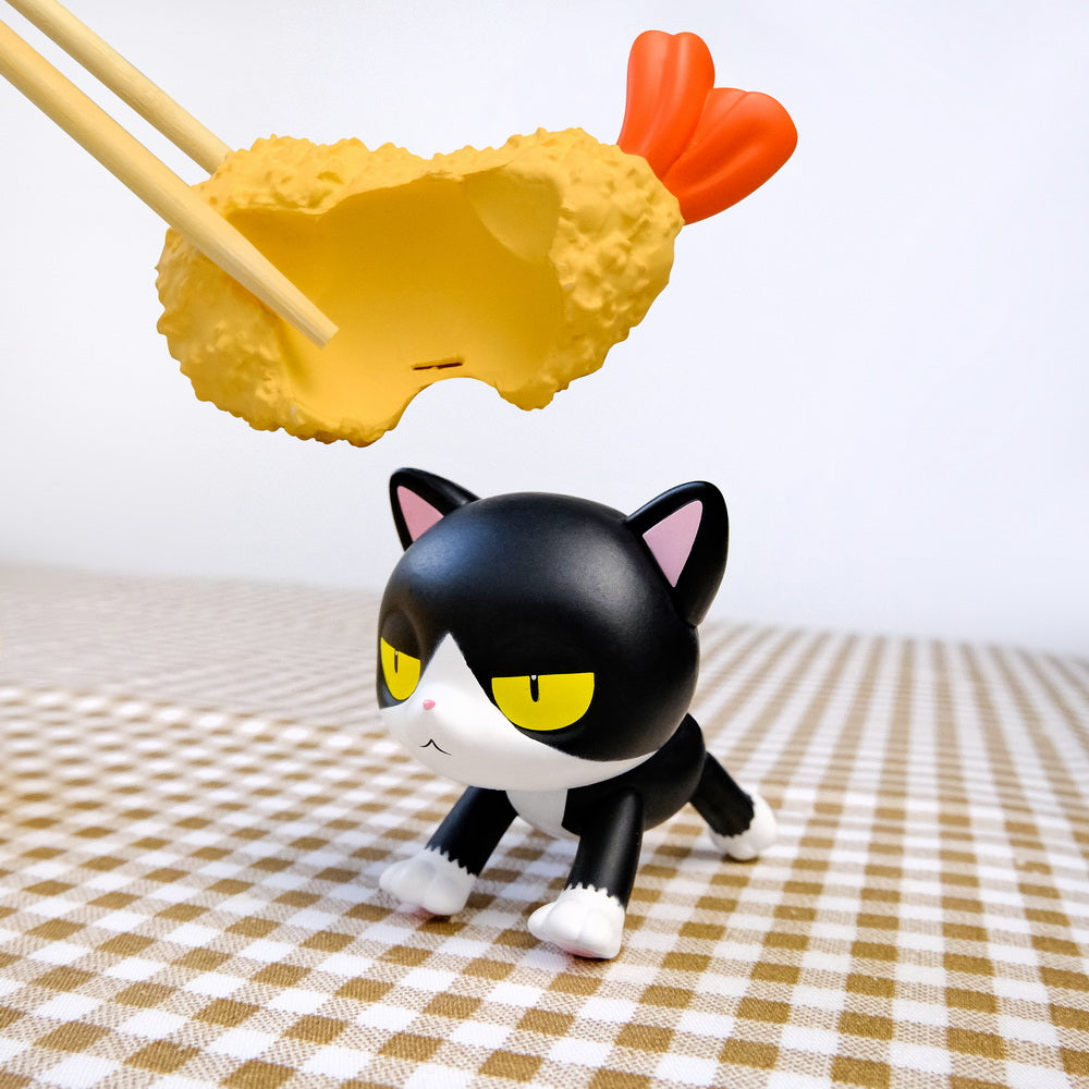Gacha Bad Cats Blindbox features a grumpy cat figurine with a tempura-style shrimp toy above it, highlighting the quirky charm of Strangecat Toys' collection.