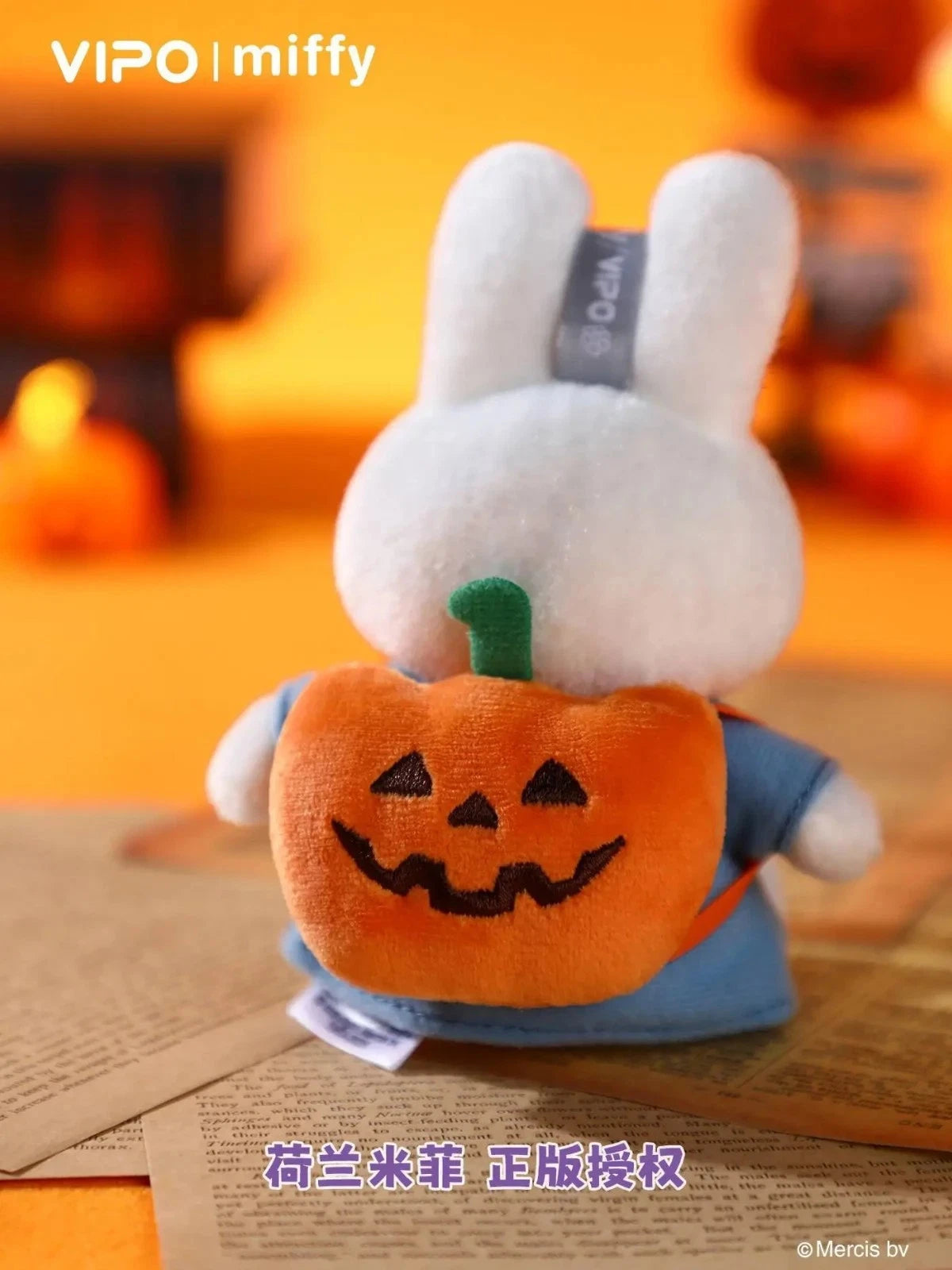 Miffy Halloween Plush Keychain Blindbox - Preorder: Back view of Miffy in blue outfit with jack-o’-lantern backpack against a Halloween backdrop.