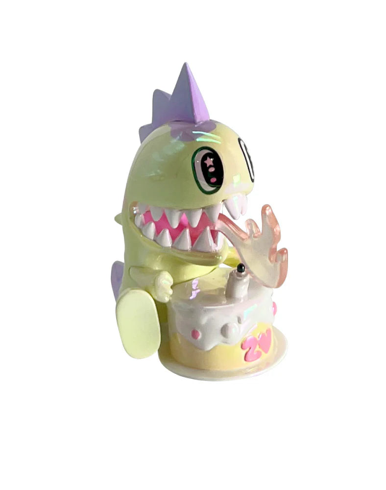 tokidoki 20th Anniversary Blind Box figure featuring a pastel dinosaur/monster with a translucent pink tongue, celebrating with a birthday cake marked “27.”