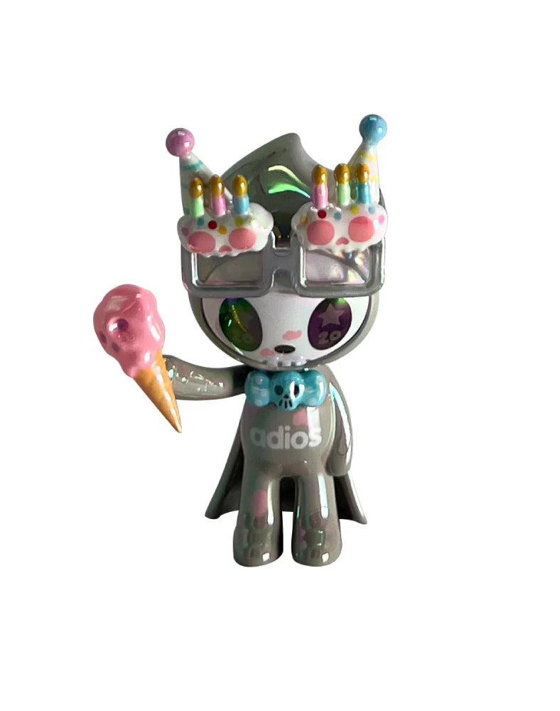 tokidoki 20th Anniversary Blind Box: Vinyl art-toy figure, humanoid with cape, glasses, party hat, holding ice cream, adios on torso, celebrating 20 years.