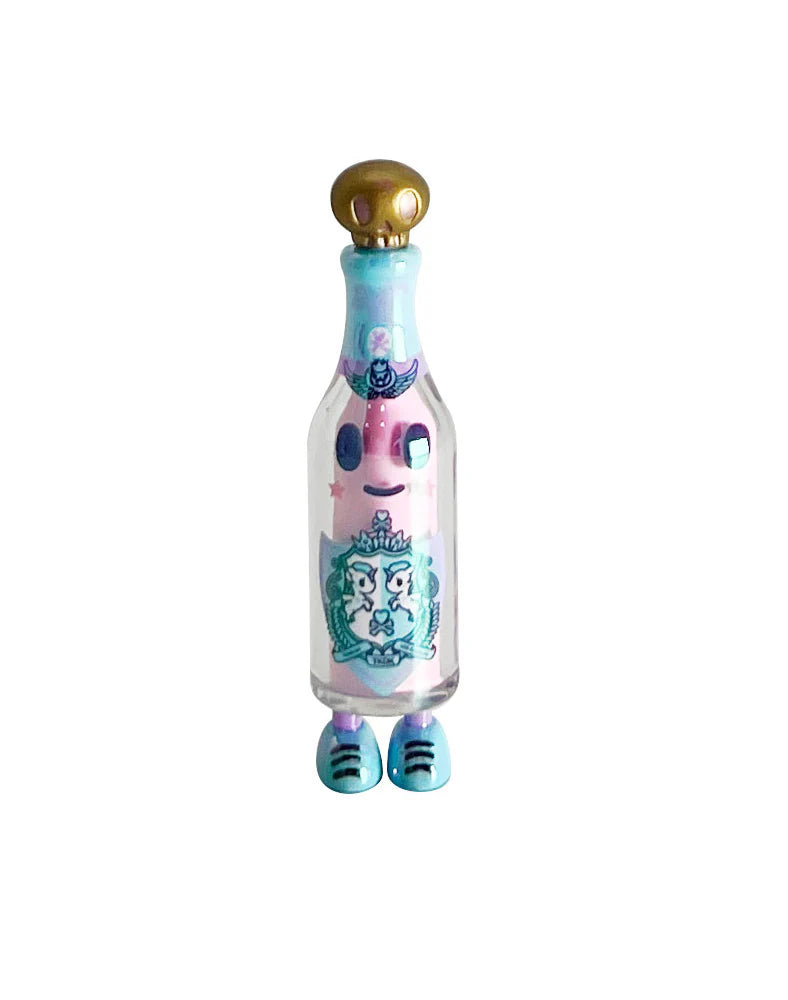 tokidoki 20th Anniversary Blind Box toy, a glass potion bottle figure with gold skull stopper, pastel-pink face insert, teal shoes, celebrating iconic characters.