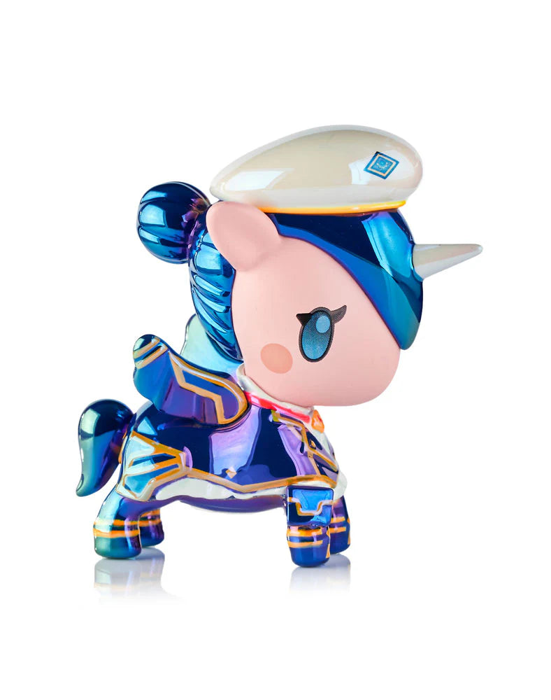 Chibi-style Unicorno figurine with metallic blue-purple body, pastel pink face, gold accents, and white cap; part of tokidoki x ARCANE Unicorno Black Light Chrome Blind Box.