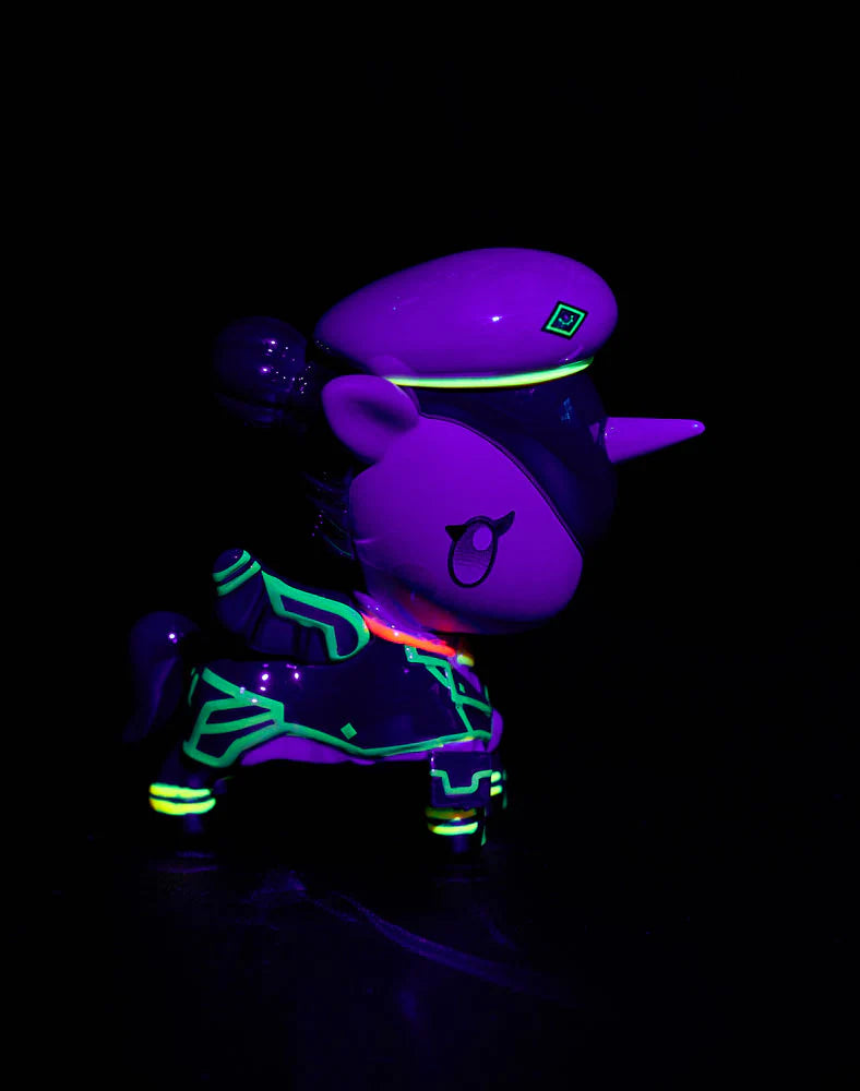 tokidoki x ARCANE Unicorno Black Light Chrome Blind Box figurine glows neon under UV light, featuring a purple shell, peaked cap, and cartoon unicorn horn.