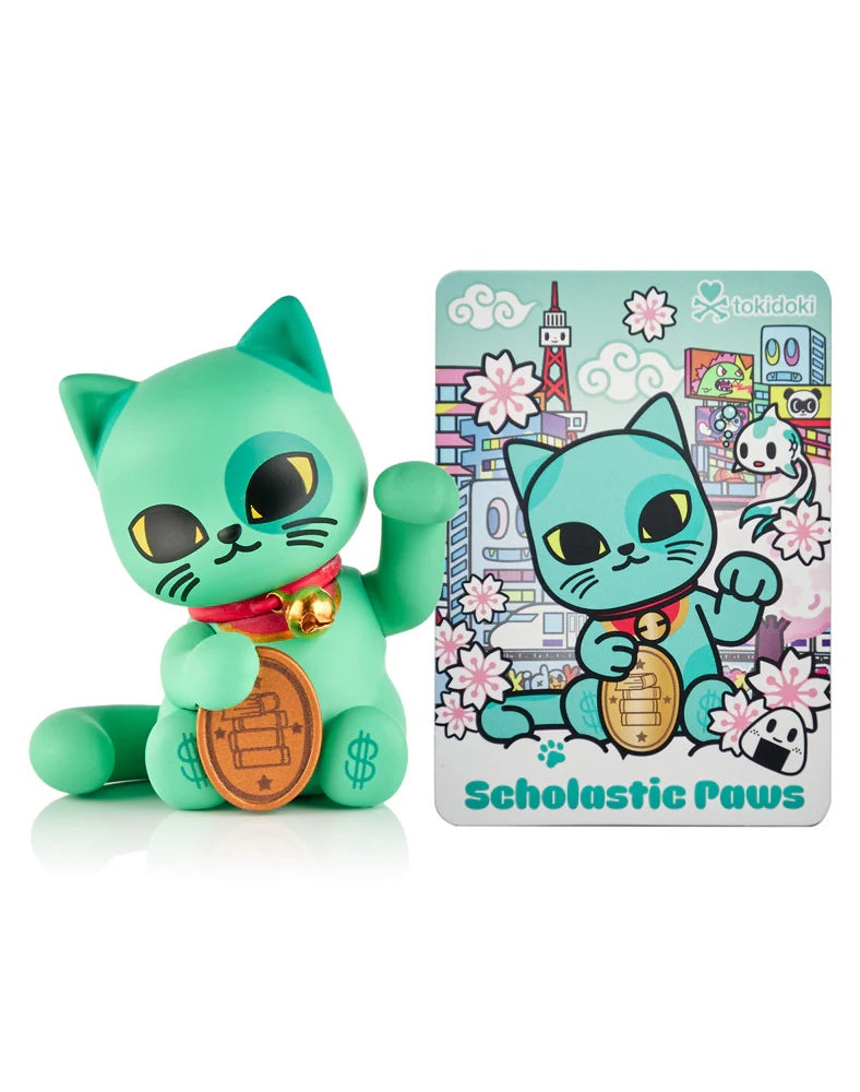 Mint-green Lucky Cats Blind Box figure by tokidoki, featuring Scholastic Paws cat with a coin and art card amidst cherry blossoms and cityscape.