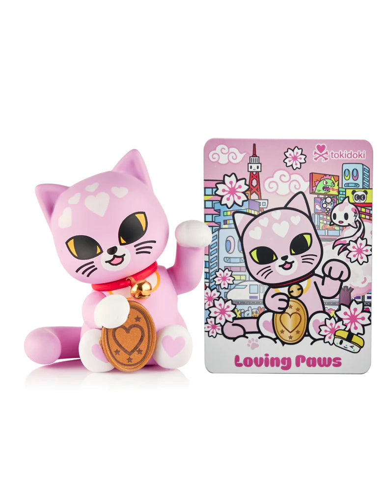 Pastel pink Lucky Cats Blind Box figure with heart motifs, holding a gold coin. Includes matching Tokidoki “Loving Paws” collector’s card.