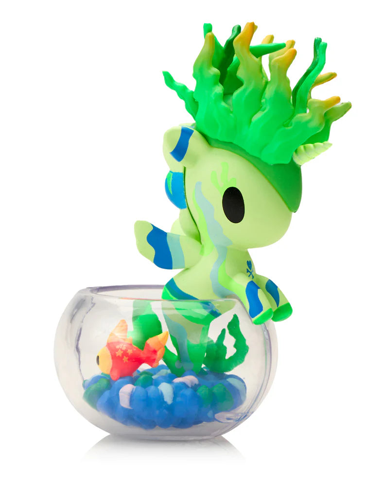 Neon Reef Mermicorno Blind Box figurine with green unicorn perched on a fishbowl, featuring blue pebbles, plant decor, and an orange fish.