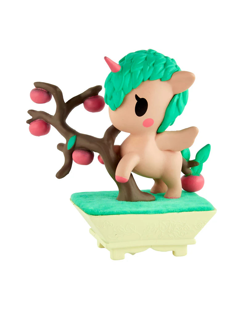 Vinyl figurine of Botanical Bonsai Unicorno, featuring a peach body, green leaf-textured hair, pink horn, leaning against a bonsai branch with reddish fruits.