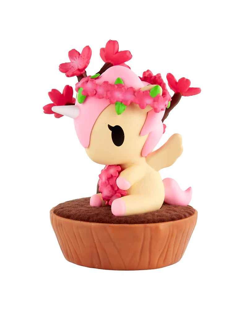 Botanical Bonsai Unicorno Blind Box figurine with cream body, pink mane, antlers with blossoms, floral wreath, and stump base, embodying kawaii bonsai art style.