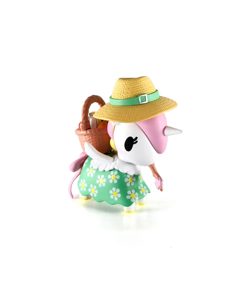 Picnic-themed Unicorno vinyl figure with pink mane, white body, green daisy skirt, straw hat, and picnic basket; part of Picnic Party Unicorno Blind Box series.