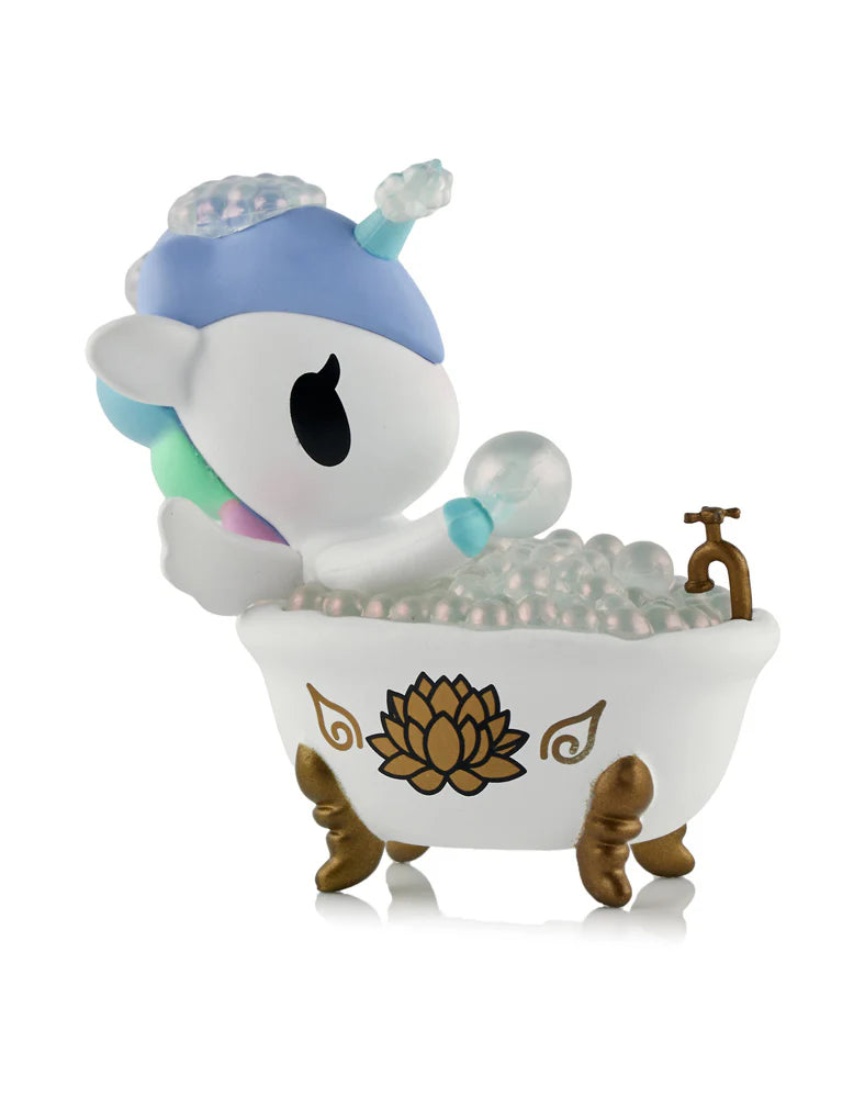 Spa Day Unicorno Blind Box - Preorder: A small unicorn figure in a gold-footed tub, holding a bubble, surrounded by pearly bubbles.