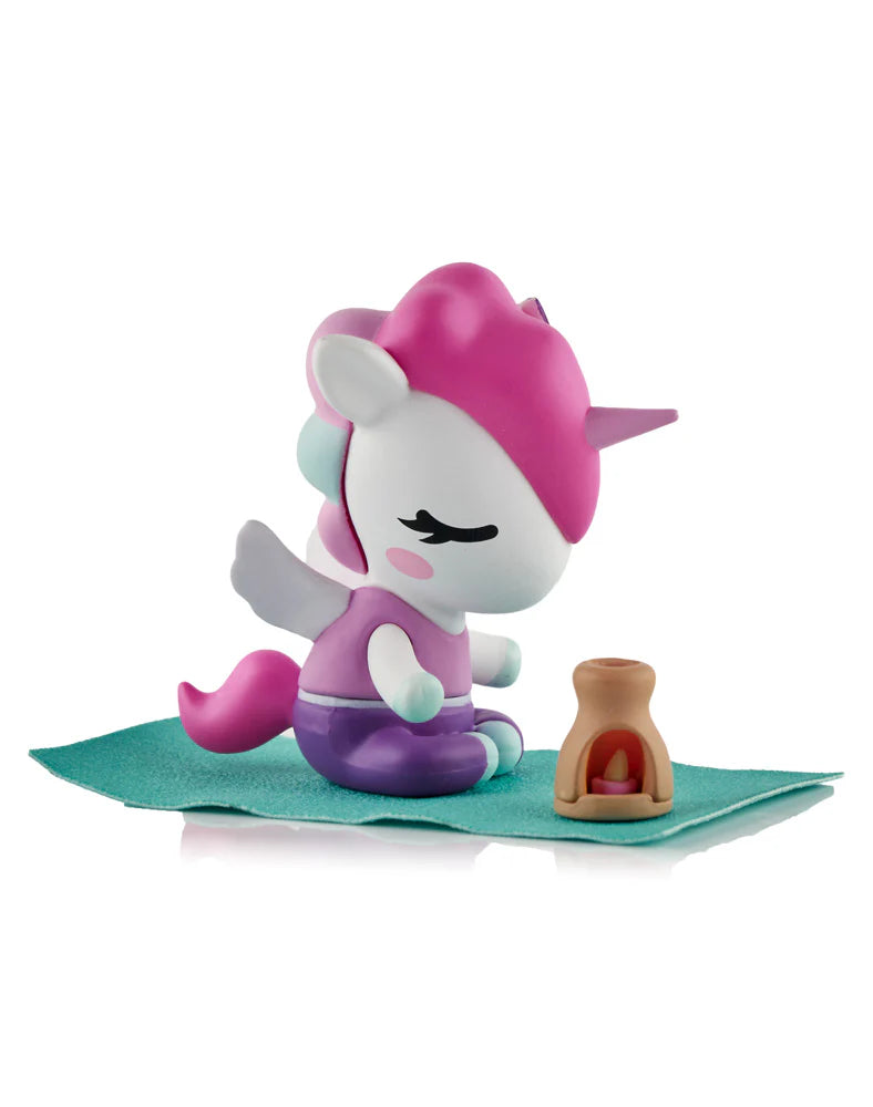 Spa Day Unicorno Blind Box - Preorder: Meditating unicorn figurine, pink mane, purple shorts, sitting on teal mat with glowing lantern, part of collectible art series.