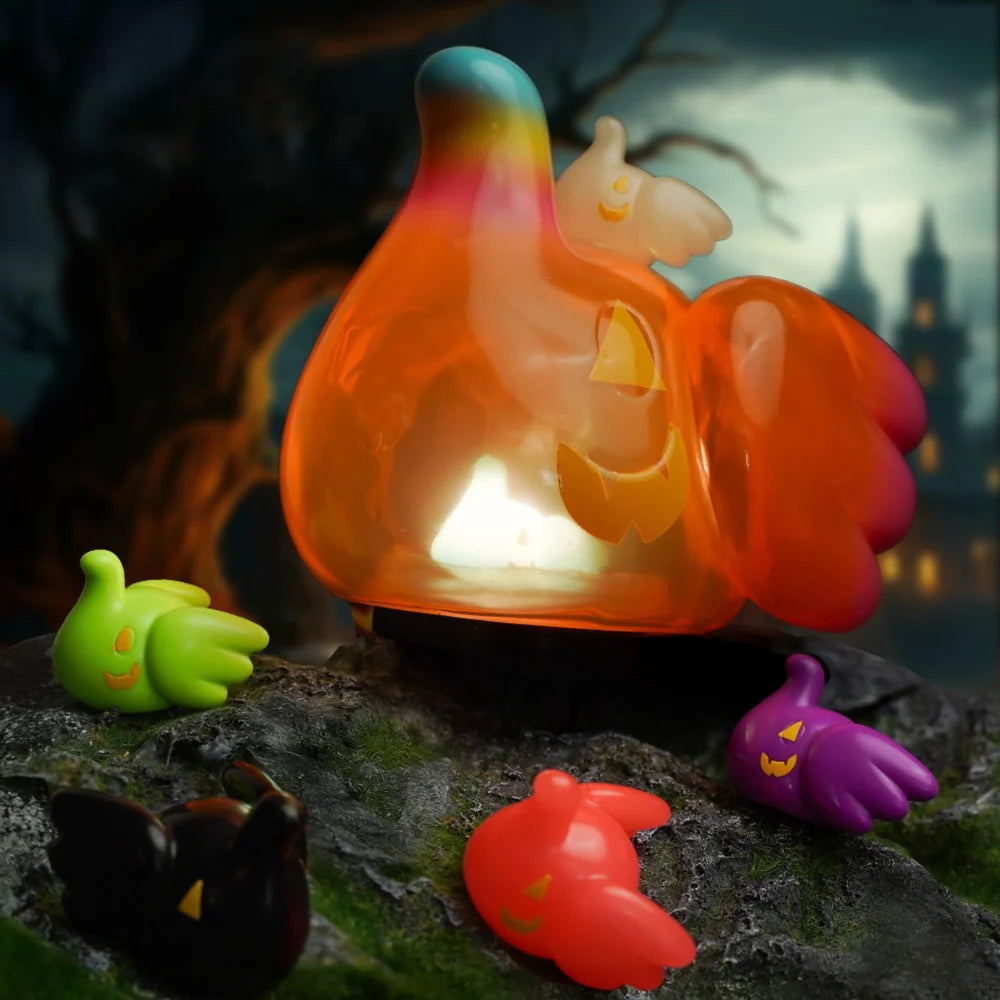 ELFIE PUMPKIN HEAD EDITION - Preorder: A glowing orange ghost figure with jack-o-lantern face, surrounded by smaller colorful ghost figures with pumpkin faces, set on mossy rock.