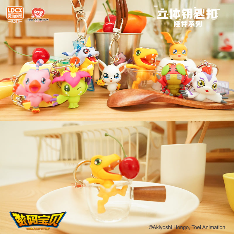 A group of Digimon toy key pendants on a table, including a white cup and a toy figurine in a glass cup.