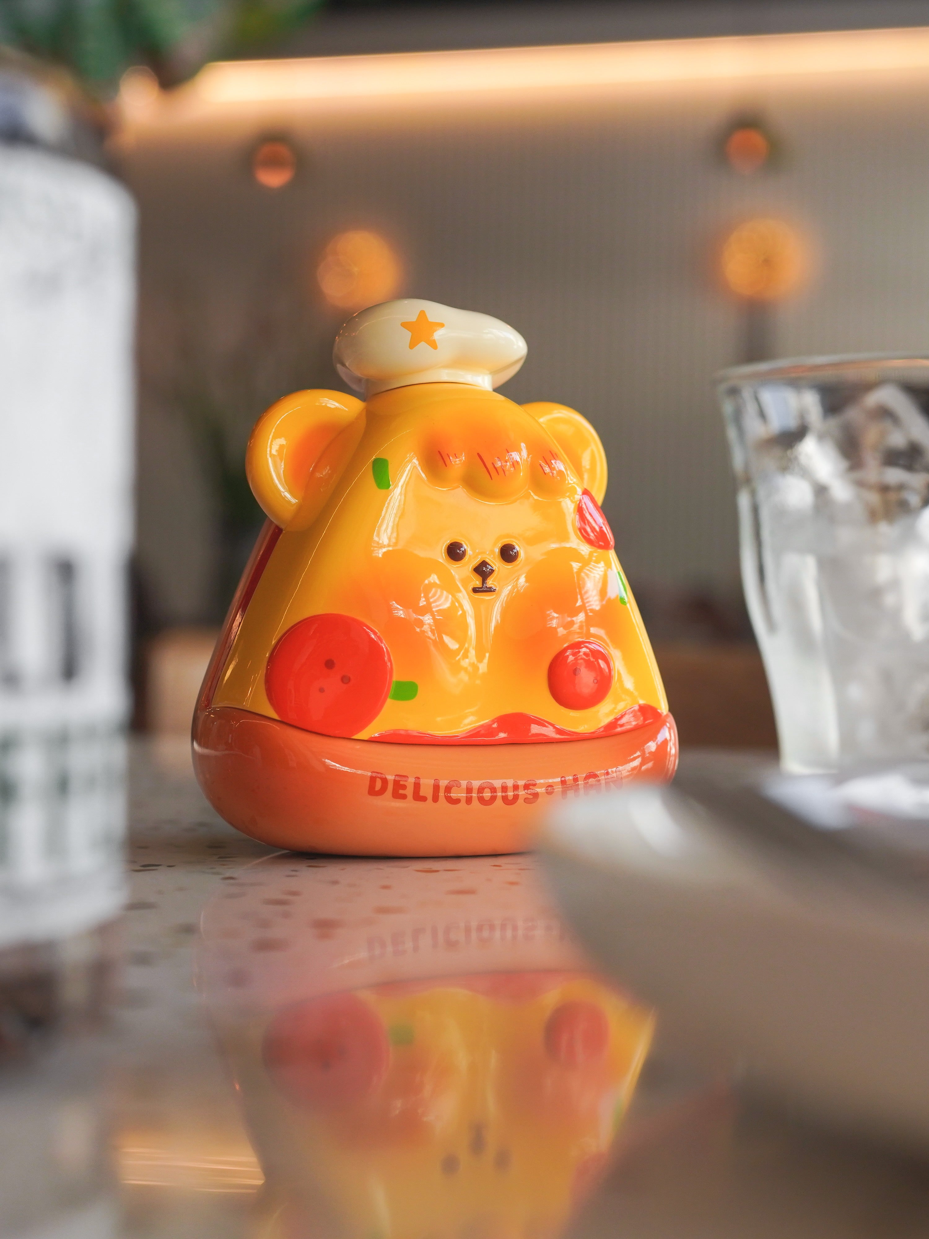 Resin toy bear on table, close-up glass, toy, button, yolk - Pizza Han Han by Unknown Island alt image.