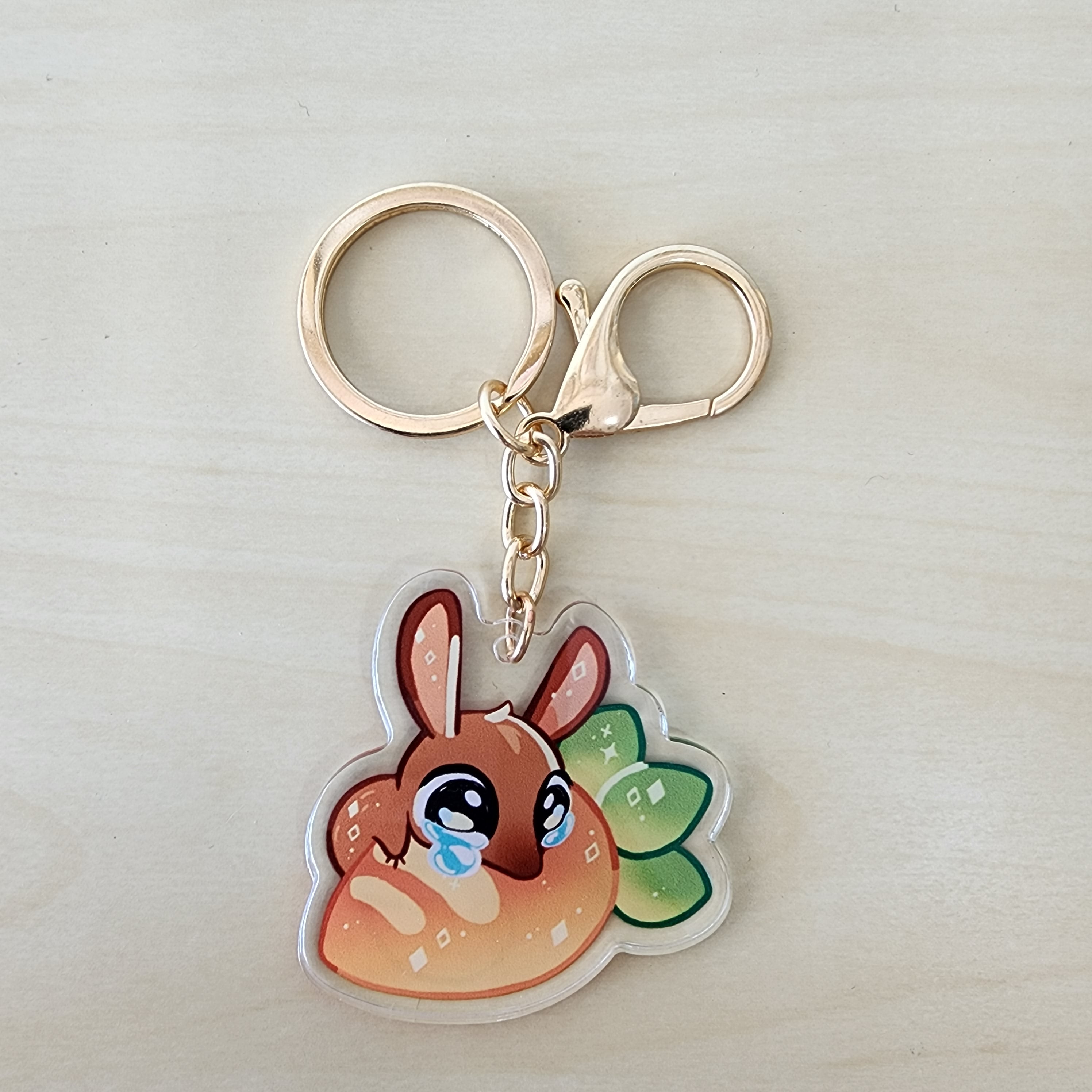 A close-up of a DeerCat Cafe - Snoo key chain with a cartoon rabbit character.