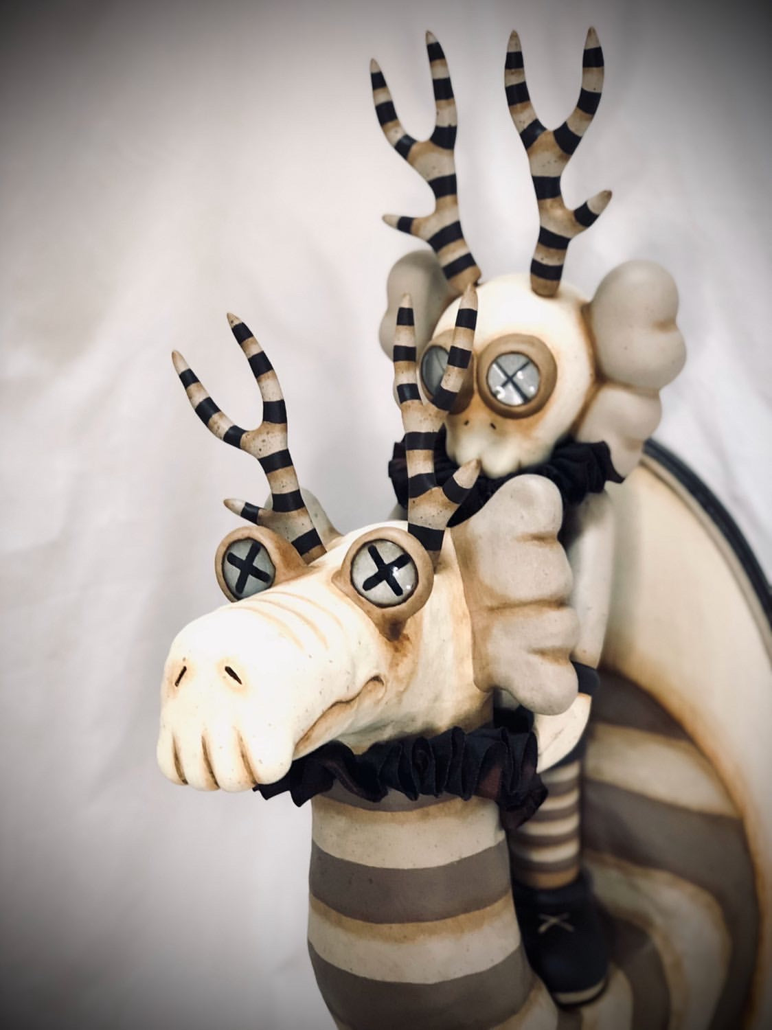 A custom show statue of a deer with horns on a circular object, striped antlers, and a cartoon eye.