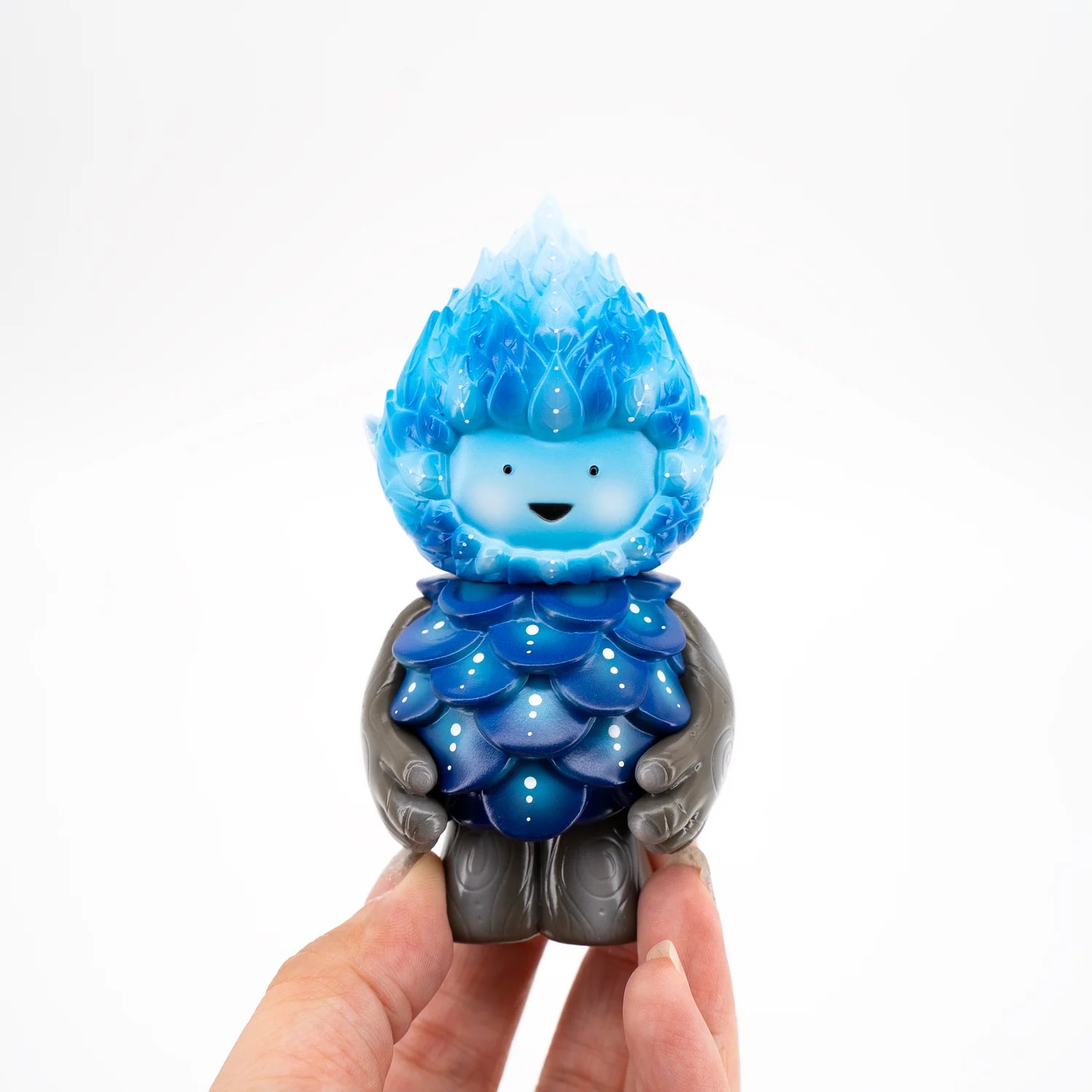 A hand holding a toy figurine of a winter spirit by Mujuworld.