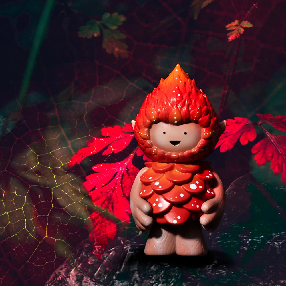A close-up of a toy in a garment held by a person, part of the MUJUWORLD MUSHROOM TREE SPIRIT collection.