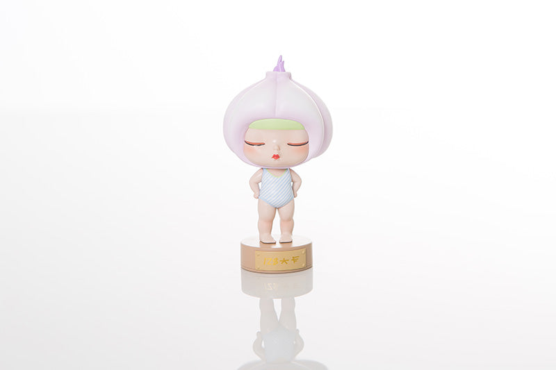 A small figurine of a baby toy, a blurry baby's bodysuit.
