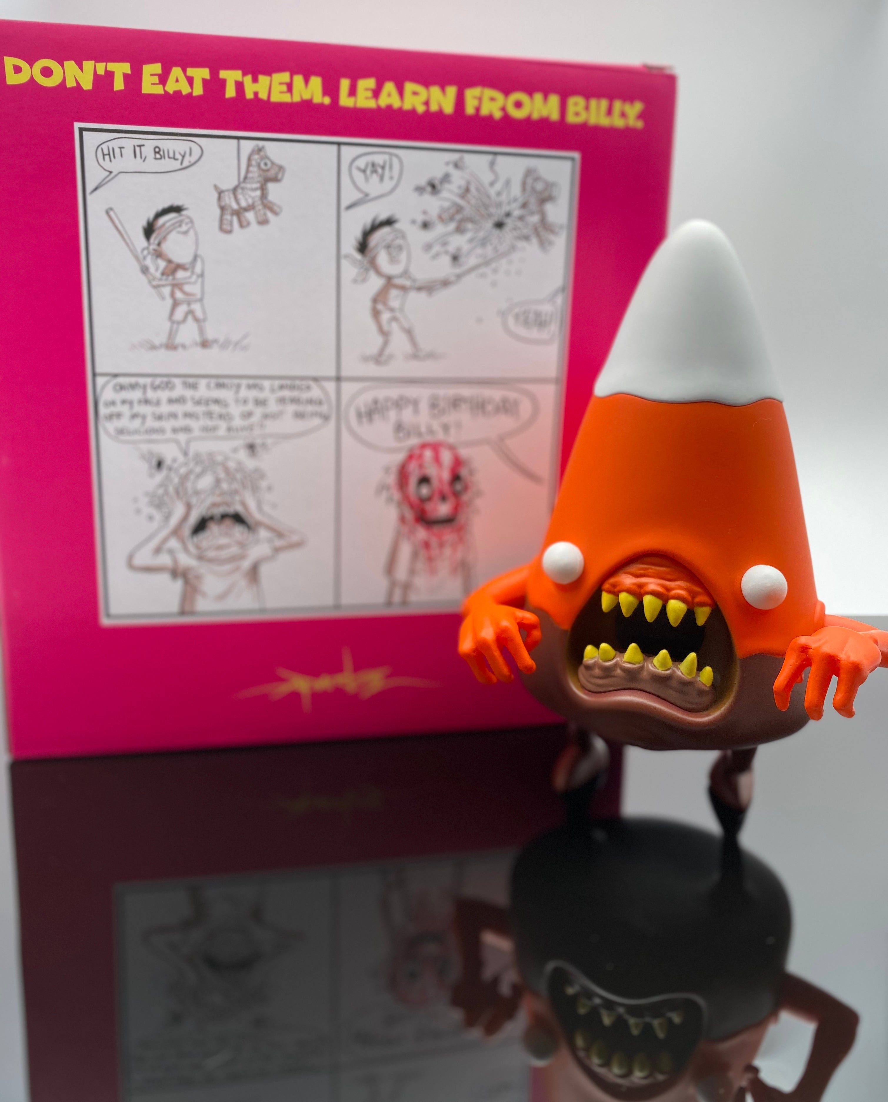Candemons - Cornelus The Candy Corn Fall Mix Exclusive toy with cartoon character, cone shape, ball, teeth, handwritten text, and person.