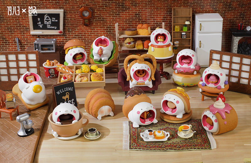 Mupa Mochie Dessert and Drink Blind Box Series toys displayed on a table with a toy in a box and a cup of hot chocolate.