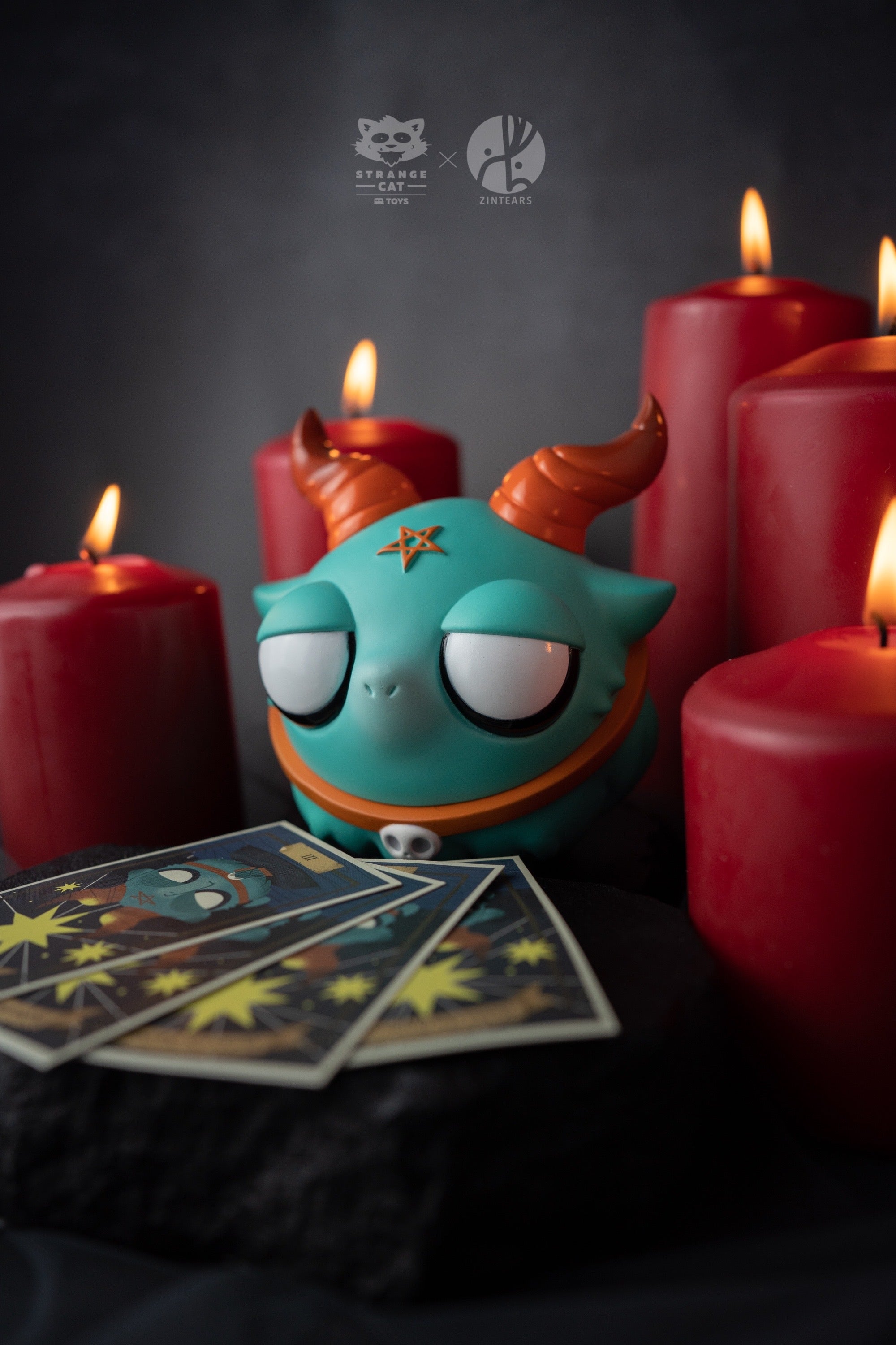 Toy figurine with candles, blue and orange toy, group of cards, star, red candle flame, Baphomet vinyl figure by Zintears.
