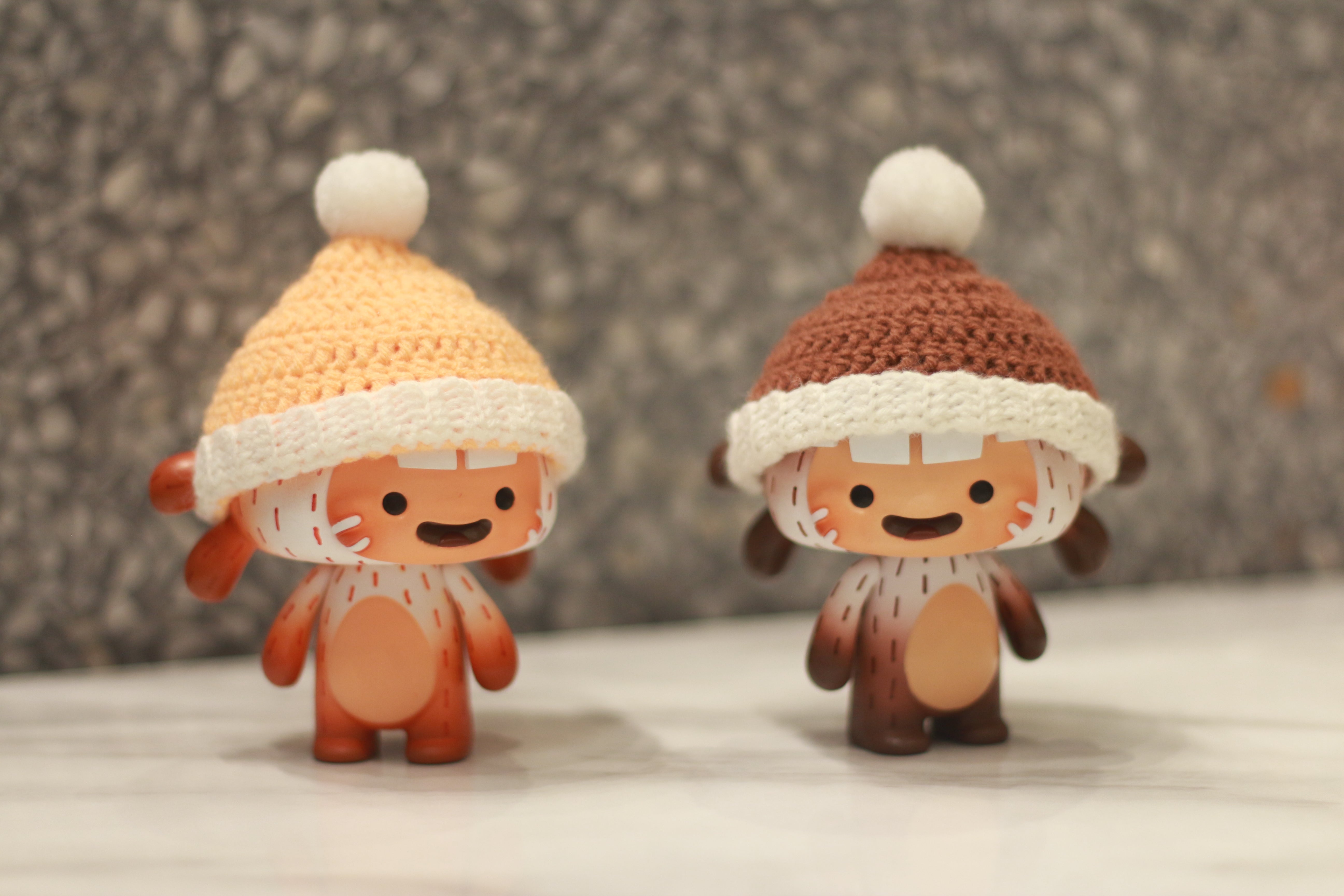 Two small toy figurines with knit hats, part of Bakumba Yeti Orange & Brown collection by Bakumba.