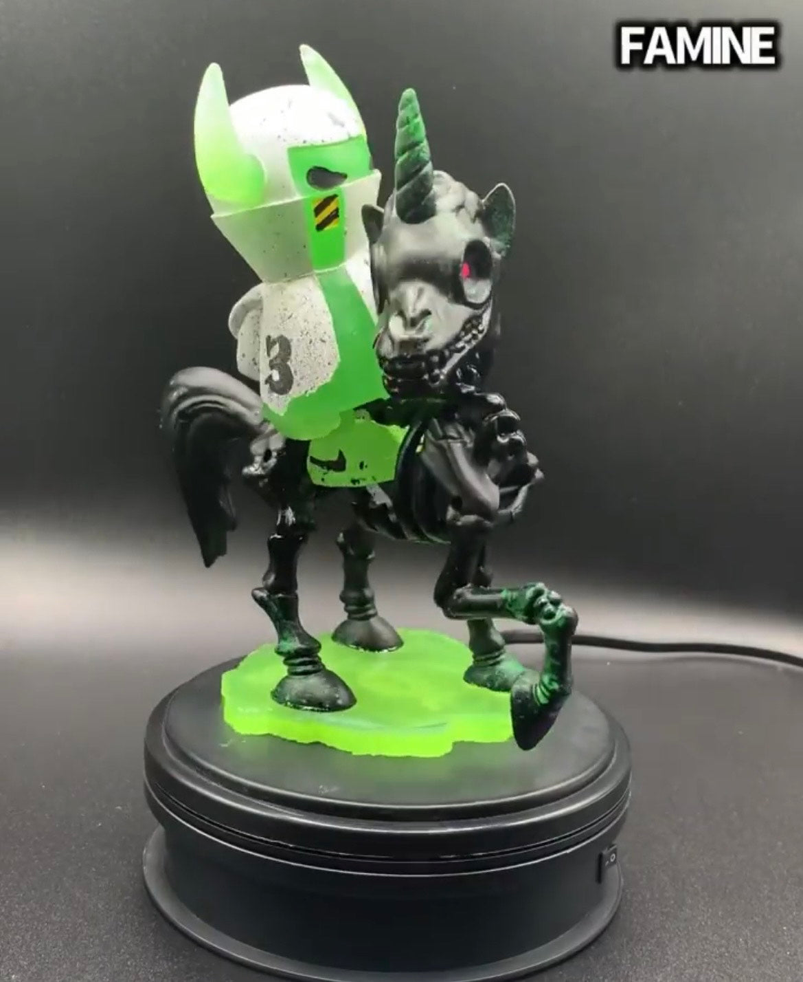 Hand Painted Resin figurine of a unicorn with a green and white object on a black stand.