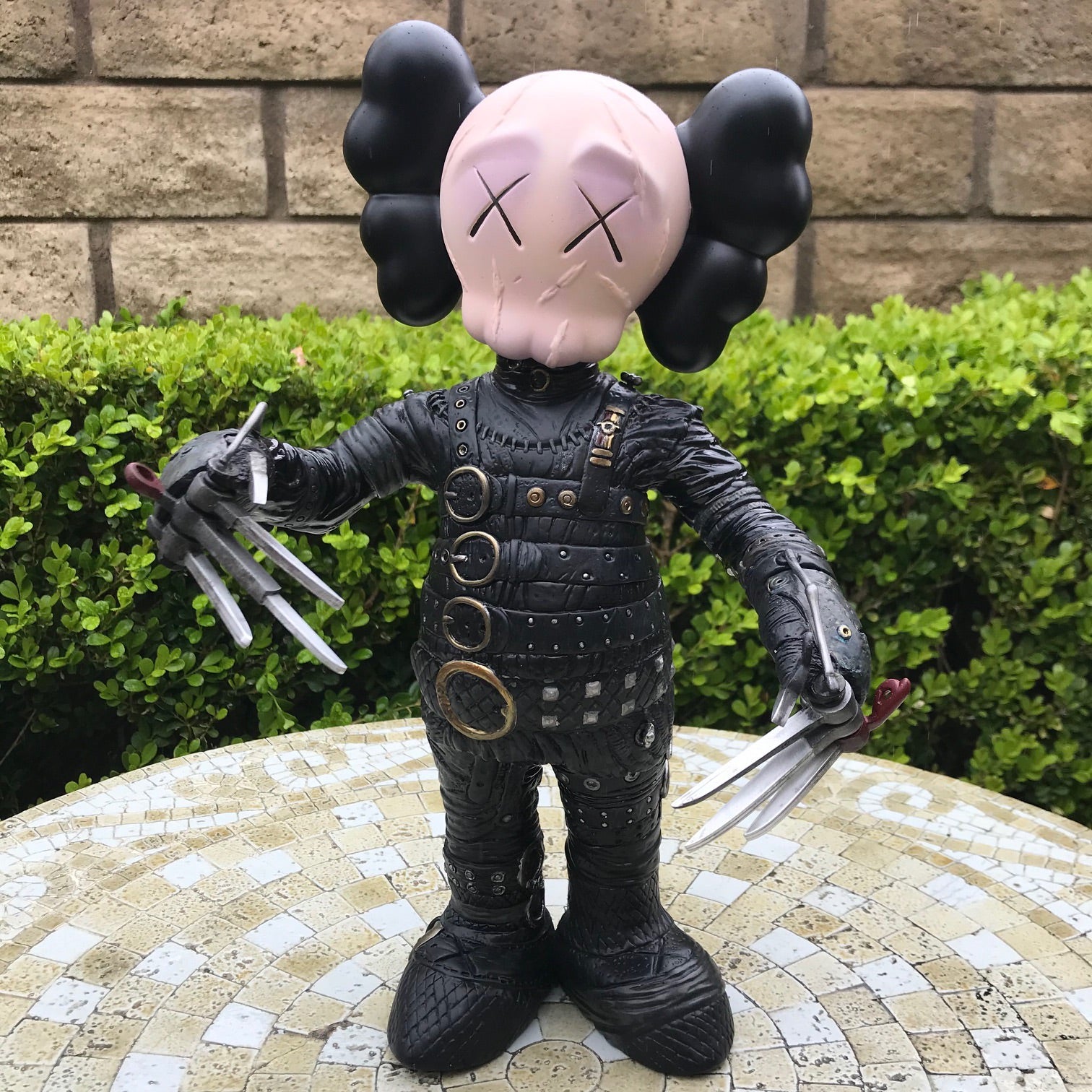 A custom toy figure with a face mask and claws on a Kaws Companion platform.
