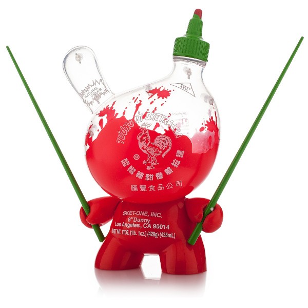 A plastic toy resembling a Sriracha bottle with chopsticks, designed by Sket-One.